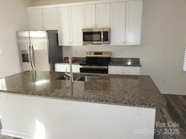 118 Carrisa Ln, Troutman, NC 28166 - kitchen featuring appliances with stainless steel finishes, dark wood finished floors, an island with sink, and white cabinets