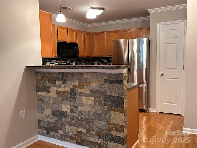 5236 Hilltop Rd, Jamestown, NC 27282 - kitchen featuring black microwave, freestanding refrigerator, dark countertops, light wood-style flooring, and brown cabinets