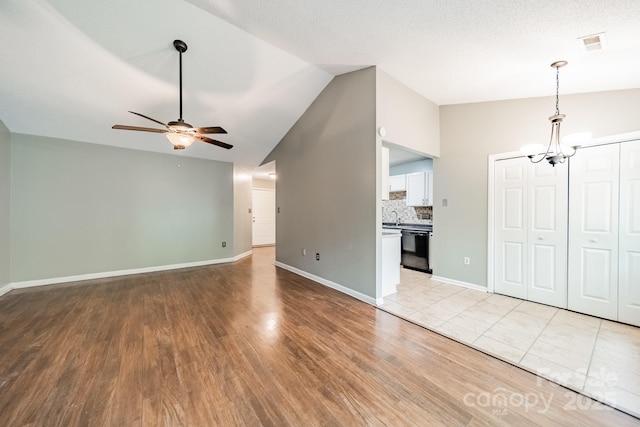 8027 Sherington Way, Charlotte, NC 28227 - unfurnished living room with lofted ceiling, a chandelier, ceiling fan, and light wood-style flooring