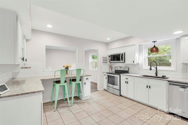 15804 Fairfield Dr, Matthews, NC 28104 - kitchen with appliances with stainless steel finishes, white cabinets, tasteful backsplash, light stone counters, and recessed lighting