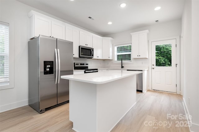 794 Stanley Spencer Mtn Rd, Gastonia, NC 28056 - kitchen featuring appliances with stainless steel finishes, light wood-type flooring, white cabinetry, a center island, and light countertops