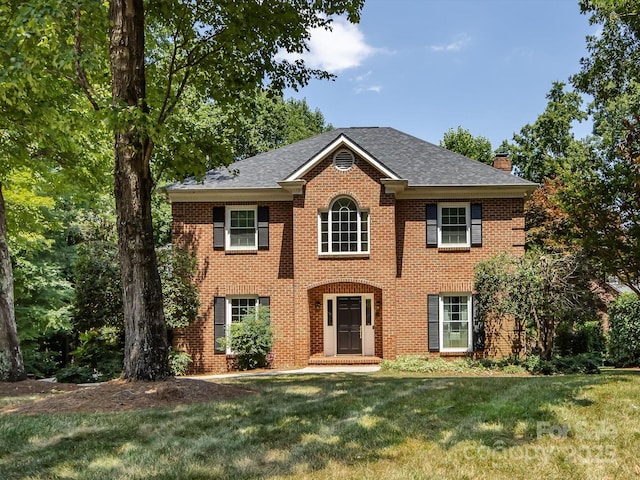 9413 Tillot Dr, Matthews, NC 28105 - colonial house featuring a chimney, brick siding, a front lawn, and a shingled roof