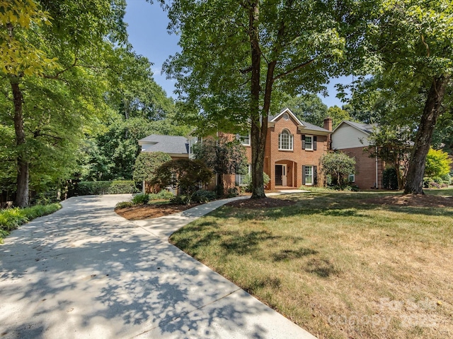 9413 Tillot Dr, Matthews, NC 28105 - colonial-style house with brick siding, driveway, a front yard, and a chimney
