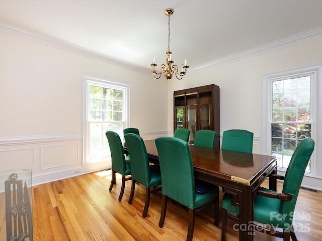 9413 Tillot Dr, Matthews, NC 28105 - dining space featuring ornamental molding, a chandelier, wainscoting, light wood finished floors, and a decorative wall