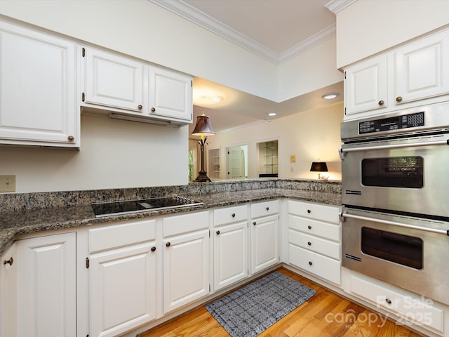 9413 Tillot Dr, Matthews, NC 28105 - kitchen with double oven, black electric stovetop, crown molding, white cabinets, and light wood-style flooring