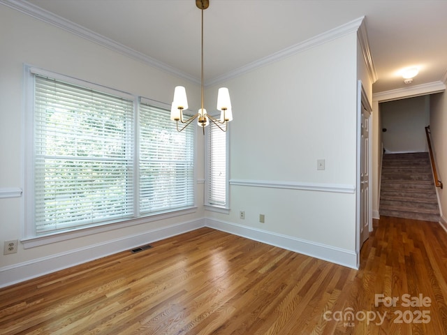 9413 Tillot Dr, Matthews, NC 28105 - unfurnished dining area with a chandelier, crown molding, wood finished floors, and stairs