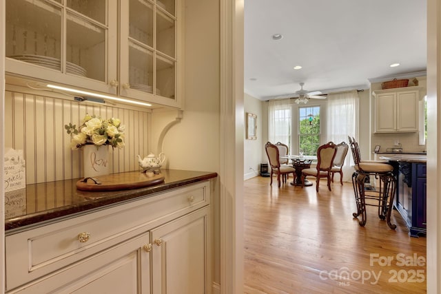 340 Harrison Rd, Roebuck, SC 29376 - kitchen featuring light wood-type flooring, crown molding, glass insert cabinets, a ceiling fan, and backsplash