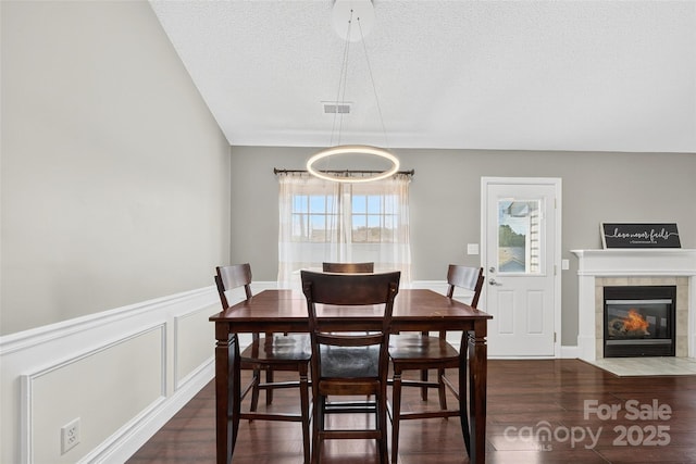 118 Milroy Ln Unit 171, Mooresville, NC 28115 - dining room featuring wood finished floors, a wainscoted wall, a textured ceiling, a fireplace, and a decorative wall
