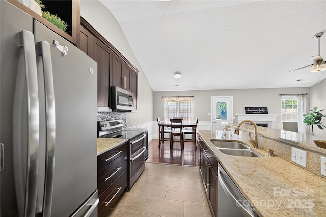 118 Milroy Ln Unit 171, Mooresville, NC 28115 - kitchen featuring stainless steel appliances, a fireplace, dark brown cabinets, light stone countertops, and vaulted ceiling