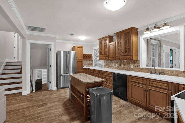 213 Turkey Hill Dr, King, NC 27021 - kitchen with brown cabinets, freestanding refrigerator, light wood-style flooring, crown molding, and tasteful backsplash