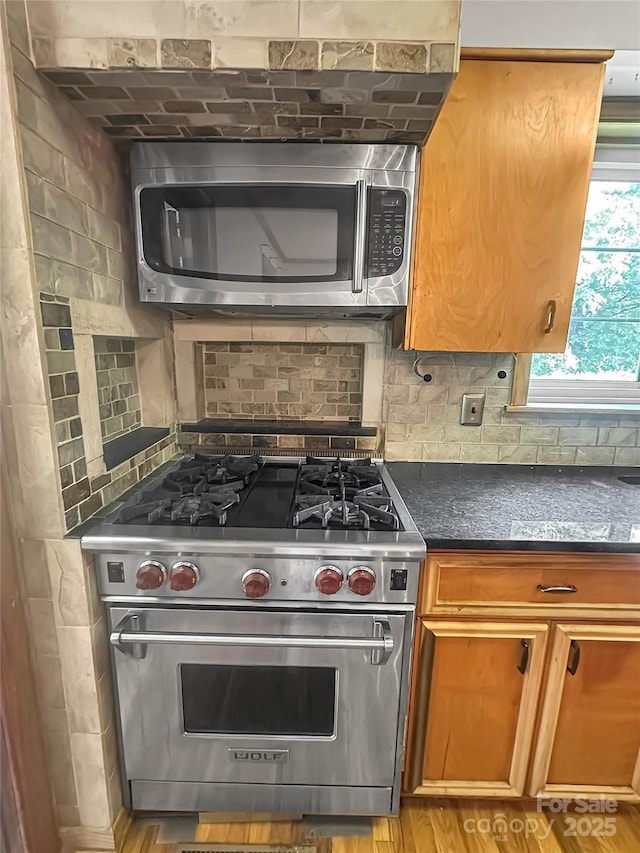 208 N Gaston St, Kings Mountain, NC 28086 - kitchen featuring appliances with stainless steel finishes, decorative backsplash, light wood-style flooring, and brown cabinetry