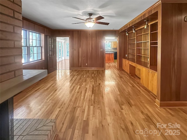 208 N Gaston St, Kings Mountain, NC 28086 - unfurnished living room featuring ceiling fan, wood walls, light wood-type flooring, and ornamental molding