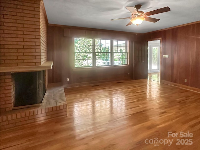 208 N Gaston St, Kings Mountain, NC 28086 - unfurnished living room featuring ceiling fan, wood finished floors, wood walls, and a brick fireplace
