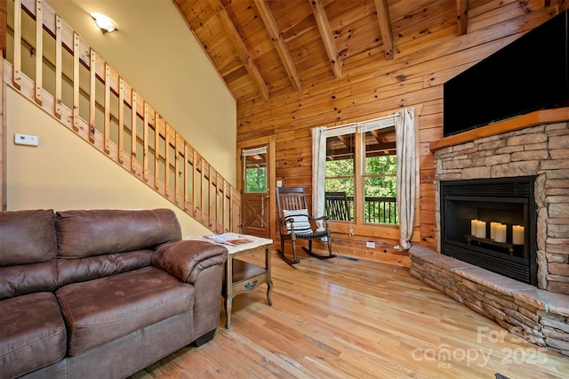 599 Shoal Creek Trl, Nebo, NC 28761 - living area featuring a wood ceiling with exposed beams, hardwood / wood-style floors, stairs, a stone fireplace, and wooden walls