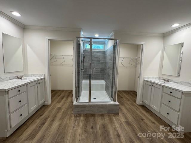 4163 Tallent Rd, Morganton, NC 28655 - full bathroom with crown molding, a stall shower, two vanities, wood finished floors, and a walk in closet