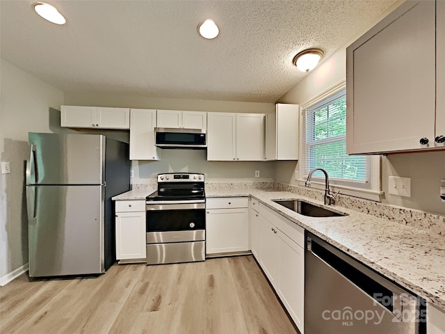 7420 Castlebar Rd, Charlotte, NC 28270 - kitchen featuring stainless steel appliances, light stone counters, light wood-type flooring, white cabinetry, and a textured ceiling