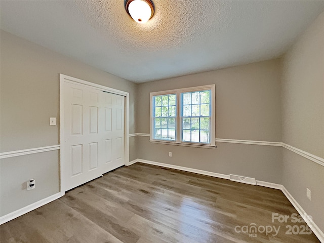 7420 Castlebar Rd, Charlotte, NC 28270 - unfurnished bedroom featuring a textured ceiling, wood finished floors, and a closet