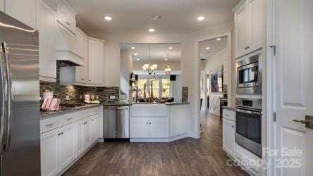 8414 Profit Ln, Charlotte, NC 28215 - kitchen with appliances with stainless steel finishes, white cabinets, custom exhaust hood, dark wood-style flooring, and recessed lighting