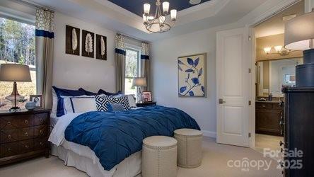 8414 Profit Ln, Charlotte, NC 28215 - bedroom featuring a chandelier, multiple windows, a raised ceiling, and light carpet