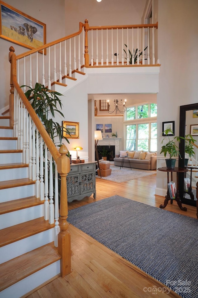 25 Madelyn Ln, Fairview, NC 28730 - stairway featuring a towering ceiling, wood finished floors, a fireplace, and a chandelier