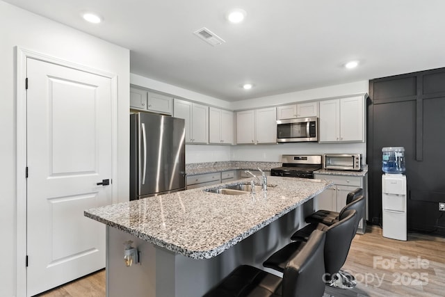 130 St James Way, Sanford, NC 27332 - kitchen with stainless steel appliances, light wood-style flooring, light stone countertops, a kitchen bar, and recessed lighting