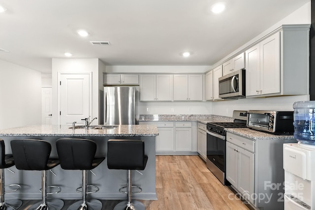 130 St James Way, Sanford, NC 27332 - kitchen featuring appliances with stainless steel finishes, a breakfast bar, light stone countertops, light wood-style flooring, and recessed lighting