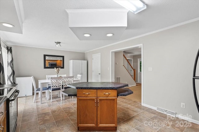 1764 Tomlinson Loop, Connelly Springs, NC 28612 - kitchen with electric stove, ornamental molding, dark countertops, a kitchen island, and brown cabinets