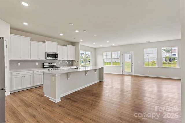 5846 Oak Branch Cir, Maiden, NC 28650 - kitchen featuring stainless steel appliances, light countertops, light wood finished floors, white cabinets, and an island with sink