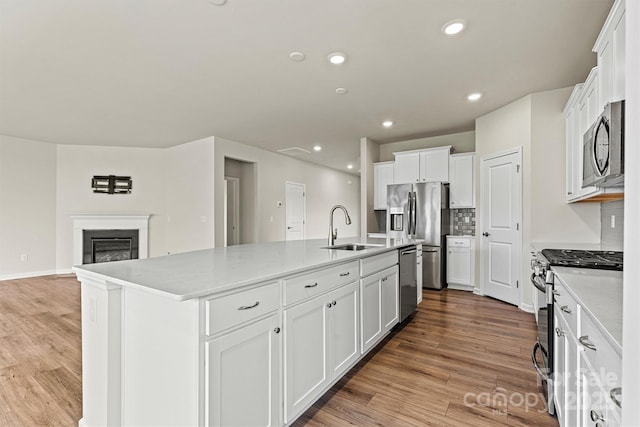 5846 Oak Branch Cir, Maiden, NC 28650 - kitchen with appliances with stainless steel finishes, a center island with sink, white cabinets, light wood-style floors, and recessed lighting