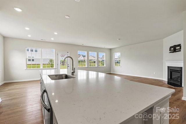 5846 Oak Branch Cir, Maiden, NC 28650 - kitchen featuring an island with sink, wood finished floors, a glass covered fireplace, light stone counters, and recessed lighting