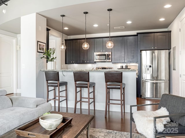 2338 Yadkin Ave Unit 505, Charlotte, NC 28205 - kitchen with appliances with stainless steel finishes, a kitchen bar, decorative light fixtures, recessed lighting, and light stone counters