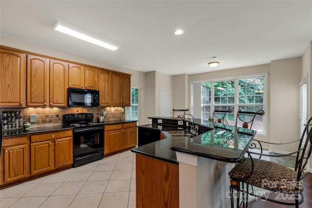 1993 W Foxwood Ct, Indian Land, SC 29707 - kitchen featuring black appliances, a kitchen breakfast bar, brown cabinets, tasteful backsplash, and dark stone countertops