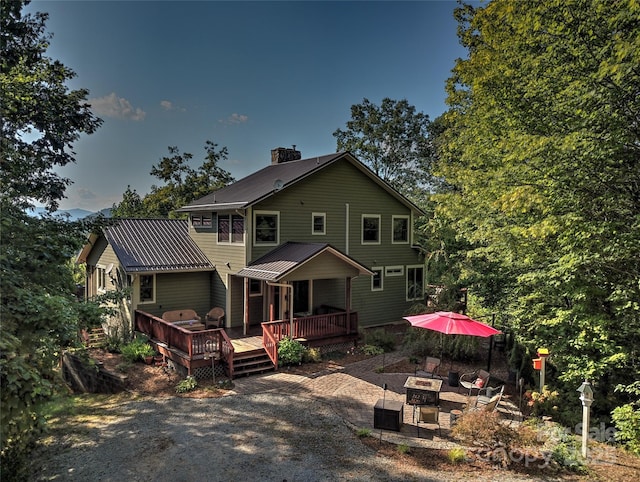 425 Sawmill Creek Rd, Bryson City, NC 28713 - back of house featuring a fire pit, a deck, a metal roof, a chimney, and a patio