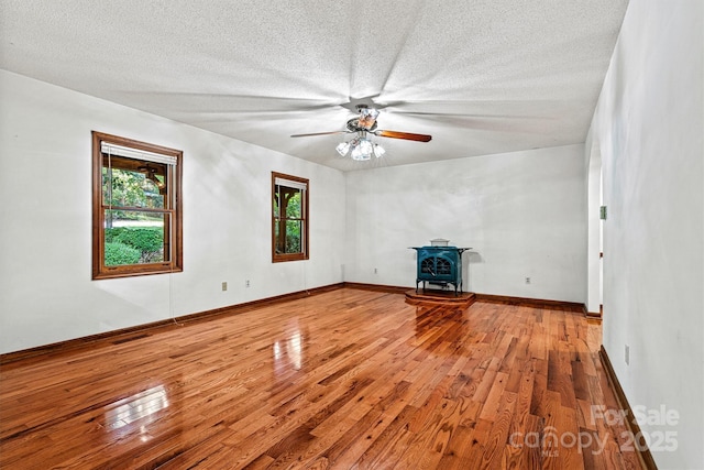 1408 Kensington Cir, Newton, NC 28658 - unfurnished living room featuring a wood stove, wood-type flooring, ceiling fan, and a textured ceiling