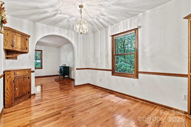 1408 Kensington Cir, Newton, NC 28658 - unfurnished dining area with arched walkways, light wood finished floors, a chandelier, a wood stove, and a textured ceiling