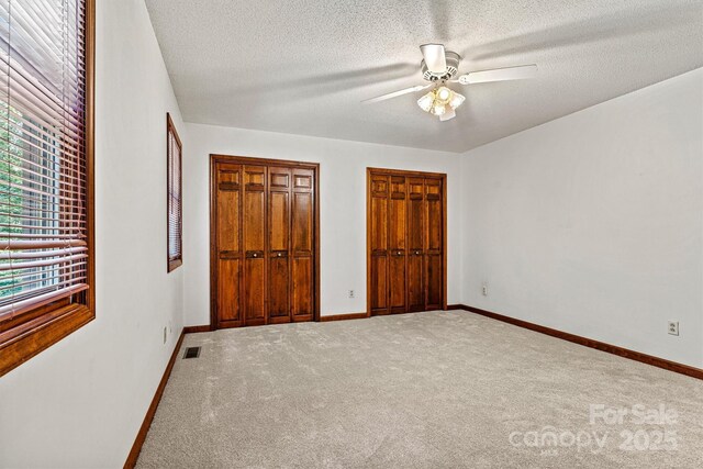 1408 Kensington Cir, Newton, NC 28658 - unfurnished bedroom with multiple windows, carpet floors, multiple closets, a textured ceiling, and ceiling fan