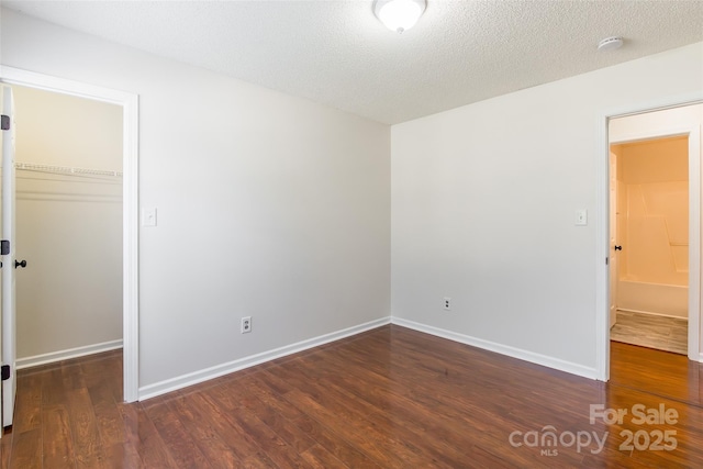 14924 Jerpoint Abby Dr, Charlotte, NC 28273 - unfurnished bedroom with wood finished floors, a spacious closet, and a textured ceiling