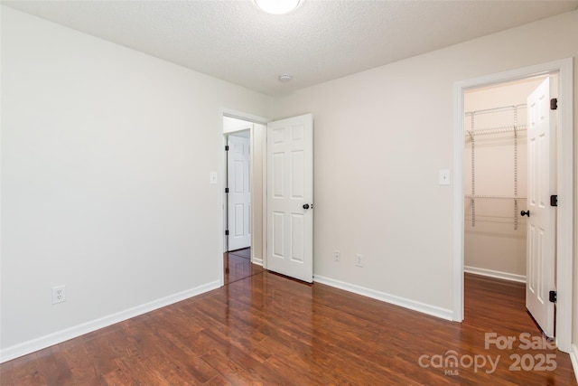 14924 Jerpoint Abby Dr, Charlotte, NC 28273 - unfurnished bedroom with a spacious closet, wood finished floors, and a textured ceiling