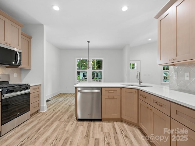 4113 Rutgers Ave, Charlotte, NC 28206 - kitchen featuring appliances with stainless steel finishes, a peninsula, light countertops, light wood-style floors, and tasteful backsplash