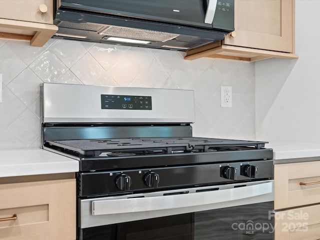 4113 Rutgers Ave, Charlotte, NC 28206 - kitchen featuring stainless steel gas range, backsplash, black microwave, and light countertops