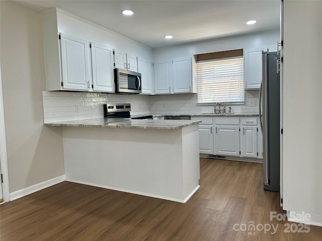 2443 1st Street Pl NW, Hickory, NC 28601 - kitchen with appliances with stainless steel finishes, a peninsula, dark wood-style floors, backsplash, and white cabinetry