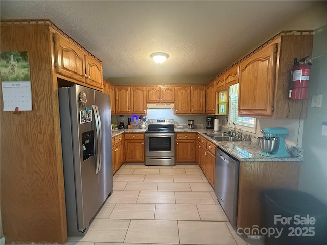 2832 Laurel Ln, Lenoir, NC 28645 - kitchen with stainless steel appliances, under cabinet range hood, brown cabinets, light tile patterned floors, and a textured ceiling