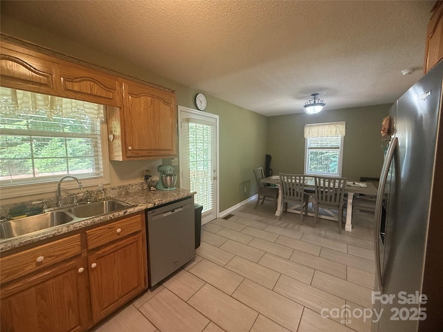 2832 Laurel Ln, Lenoir, NC 28645 - kitchen with appliances with stainless steel finishes, brown cabinetry, a textured ceiling, light tile patterned floors, and light stone countertops