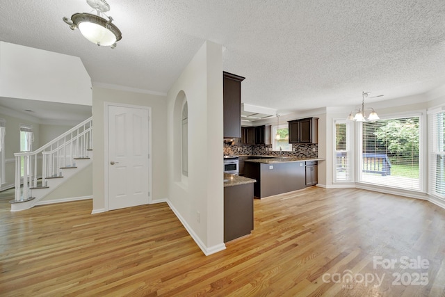 10807 Summitt Tree Ct, Charlotte, NC 28277 - kitchen with dark brown cabinetry, light wood-style floors, a chandelier, a textured ceiling, and tasteful backsplash