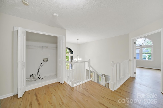 10807 Summitt Tree Ct, Charlotte, NC 28277 - hallway featuring an upstairs landing, wood finished floors, a chandelier, healthy amount of natural light, and a textured ceiling