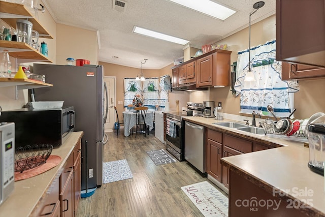 115 Red Fox Ct, Mount Holly, NC 28120 - kitchen with appliances with stainless steel finishes, light wood finished floors, brown cabinets, a textured ceiling, and hanging light fixtures