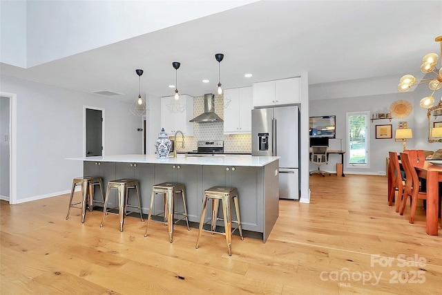 4906 Crooked Oak Ln, Charlotte, NC 28226 - kitchen with appliances with stainless steel finishes, wall chimney range hood, light wood-style flooring, backsplash, and recessed lighting