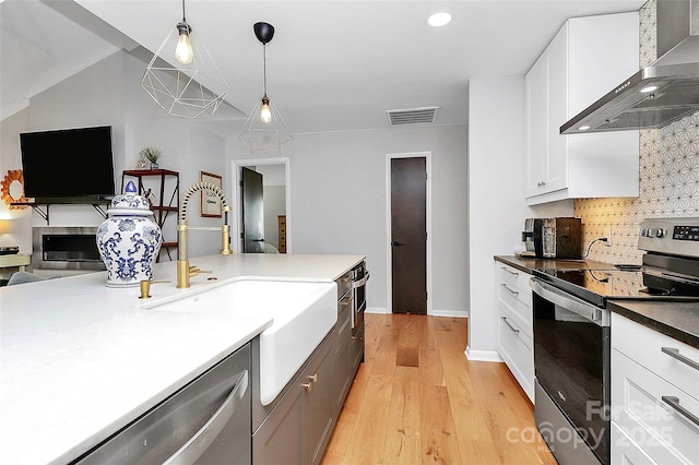 4906 Crooked Oak Ln, Charlotte, NC 28226 - kitchen with stainless steel appliances, wall chimney range hood, backsplash, open floor plan, and light wood-style floors
