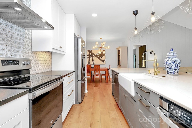 4906 Crooked Oak Ln, Charlotte, NC 28226 - kitchen with stainless steel appliances, range hood, backsplash, light wood-type flooring, and a chandelier