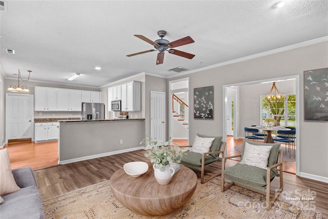 145 Summerbrook Ln, Mooresville, NC 28117 - living room with light wood-style floors, crown molding, a chandelier, stairs, and a textured ceiling